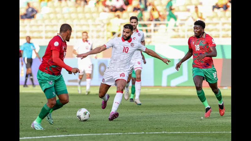 Cầu thủ Tunisia với áo đỏ đang nỗ lực vượt qua cầu thủ Namibia trong trận đấu bóng đá. Cầu thủ Tunisia với áo đỏ đang nỗ lực vượt qua cầu thủ Namibia trong trận đấu bóng đá.